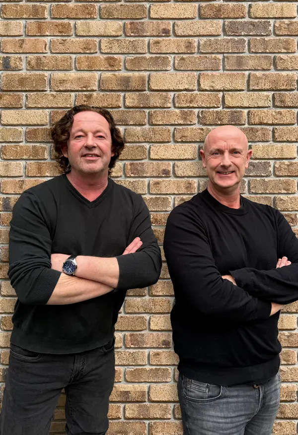 Pascal en Richard Hensen, met de armen over elkaar voor een bakstenen muur