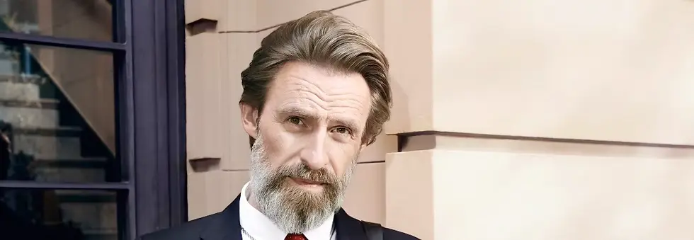 Man met grijze baard en verzorgd kapsel in pak