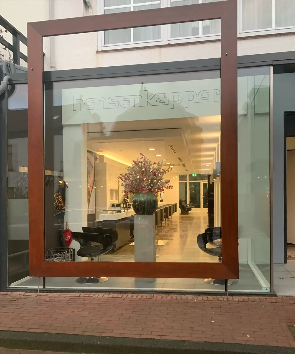 De winkelpui van Hensen Kappers met het logo op het raam